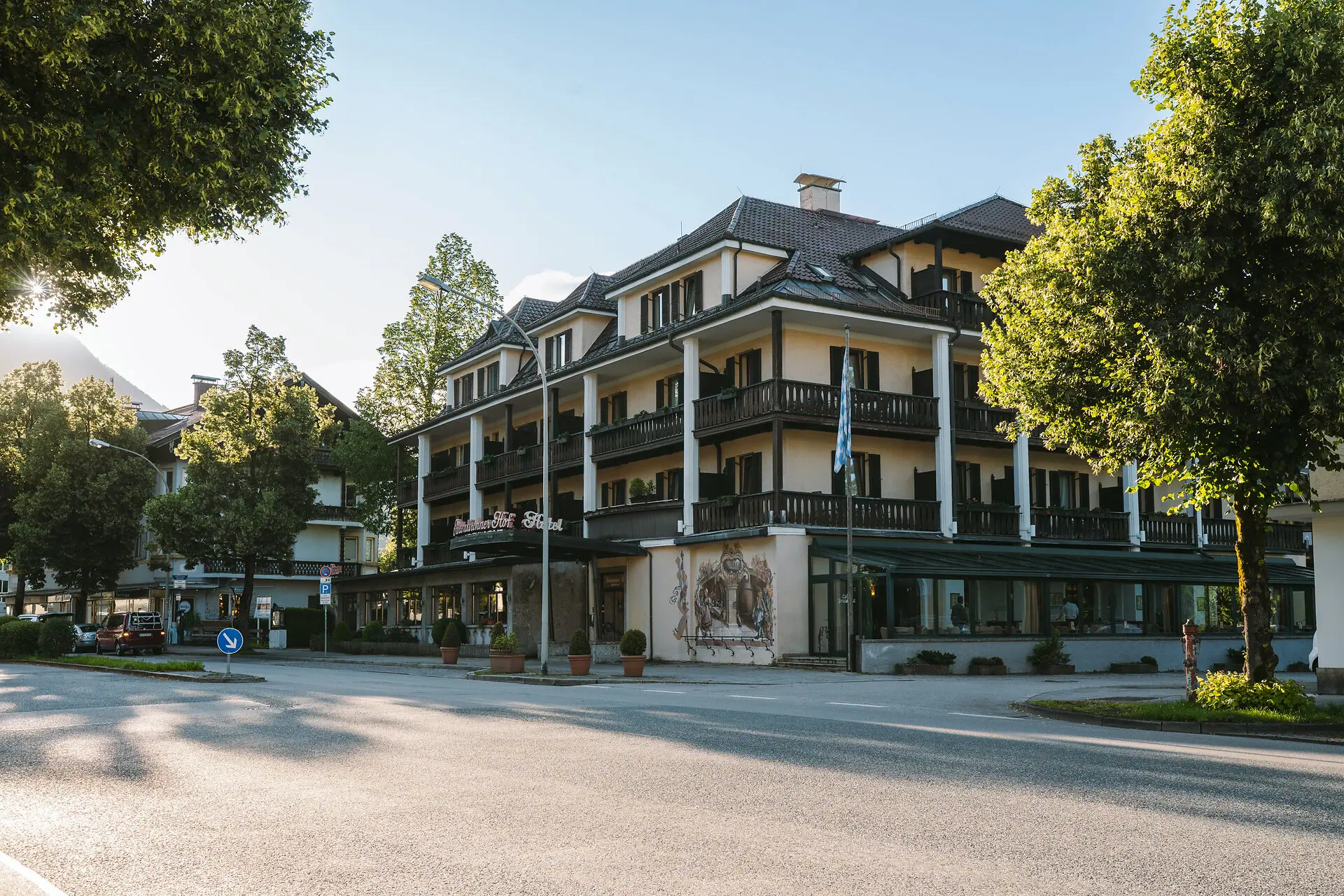 Die Außenansicht vom HENRI Hotel Garmisch-Partenkirchen mit Bäumen und einer Straße.