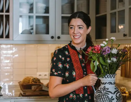 Eine Frau hält eine Vase mit Blumen.